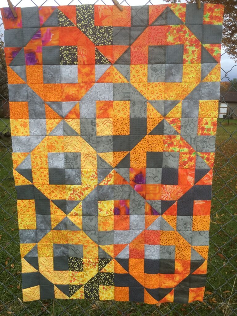An orange and gray quilt with O shaped pattern.